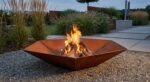 Corten steel hexagonal fire pit Diamond Hex burning wood in modern garden
